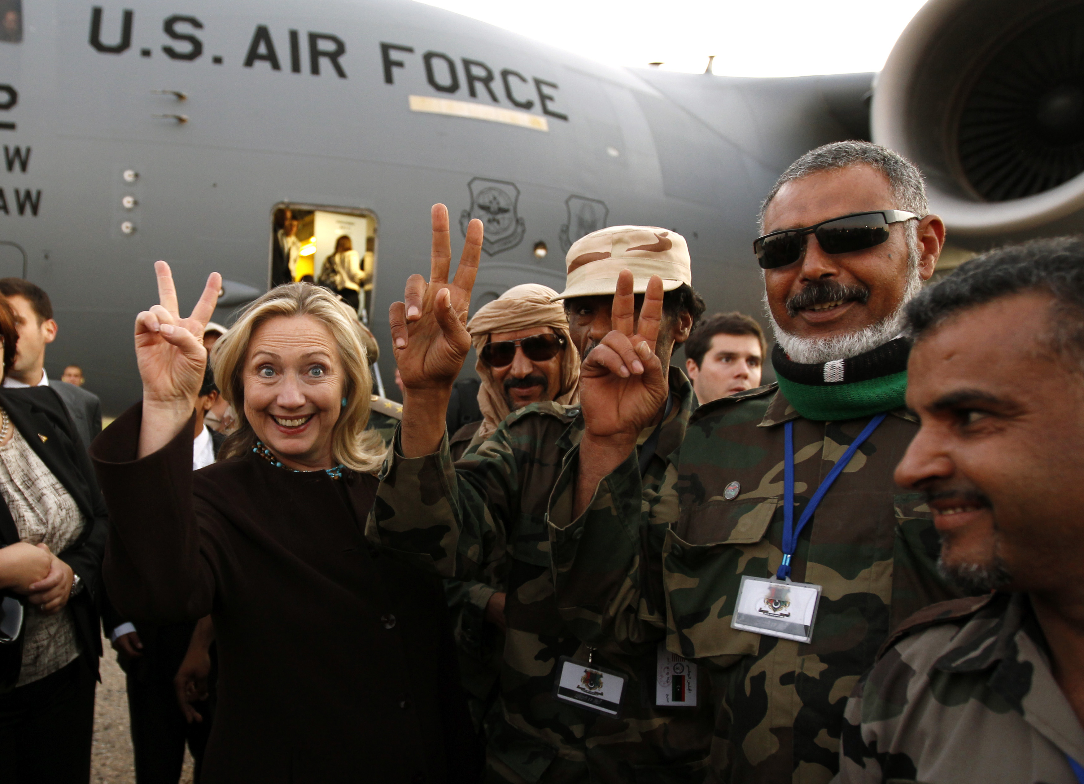 U.S. Secretary of State Hillary Clinton gestures with Libyan soldiers upon her departure from Tripoli in Libya